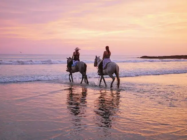 Two riders on the beach at sunset